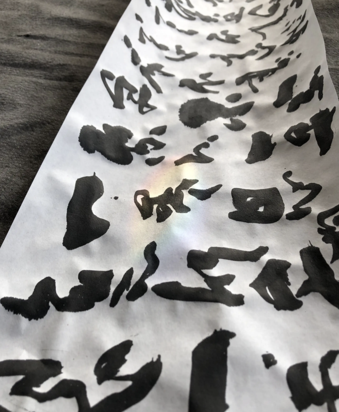 Light refracts onto the wrinkled scroll paper with ink.